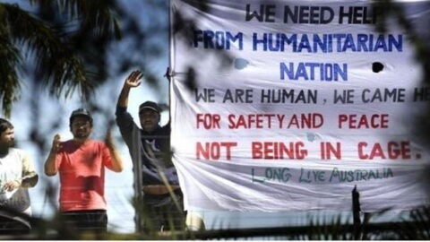 Men standing on top of building with signs adking for help