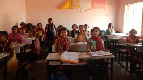 Cute Indian schoolgirls seated at desks