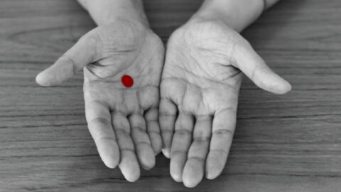 Photo of outstretched hands, one with a red dot