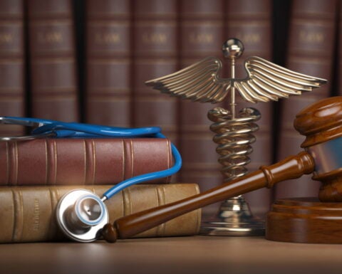 Gavel, stethoscope and caduceus sign on books background