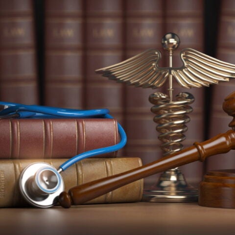 Gavel, stethoscope and caduceus sign on books background
