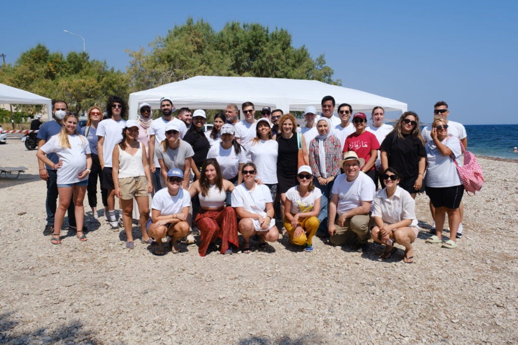 2024 cohort of intensive summer course on migration and refugee studies in Greece posing for group photo by the sea in Lesvos, Greece.