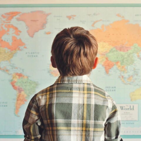 Image of boy looking at map of the world. Moment/Getty