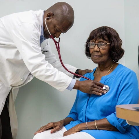 Morris Brown, a primary care physician, listens to Sarah McCutcheon’s heartbeat in the exam room at his medical office in Kingstree, South Carolina, which sits in a region that suffers from health care provider shortages and high rates of chronic diseases. (Gavin McIntyre for KFF Health News)