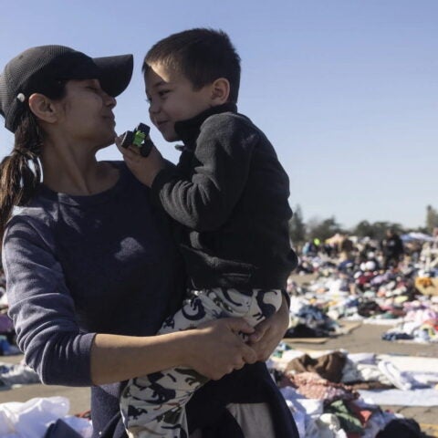 Zahrah Mihm (L) holds her son Ethan as they look for clothes after being displaced by the Eaton Fire, at a donation center in Santa Anita Park, Arcadia. Etienne Laurent/AFP via Getty Images.