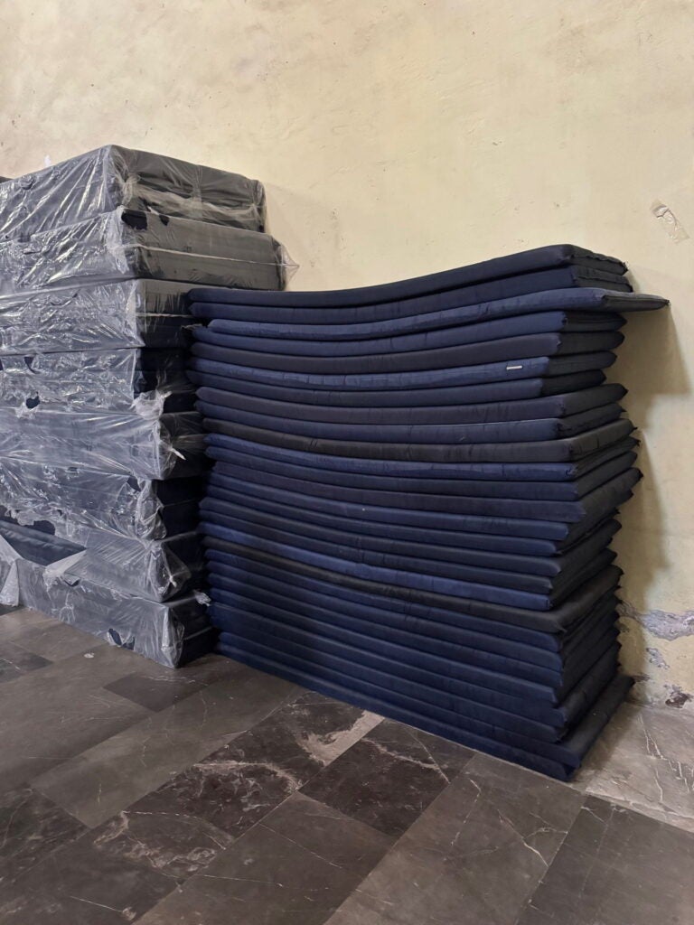 Mexico 2025, stack of thin blue, single mattresses against a wall. Photo courtesy of Jacqueline Bhabha.