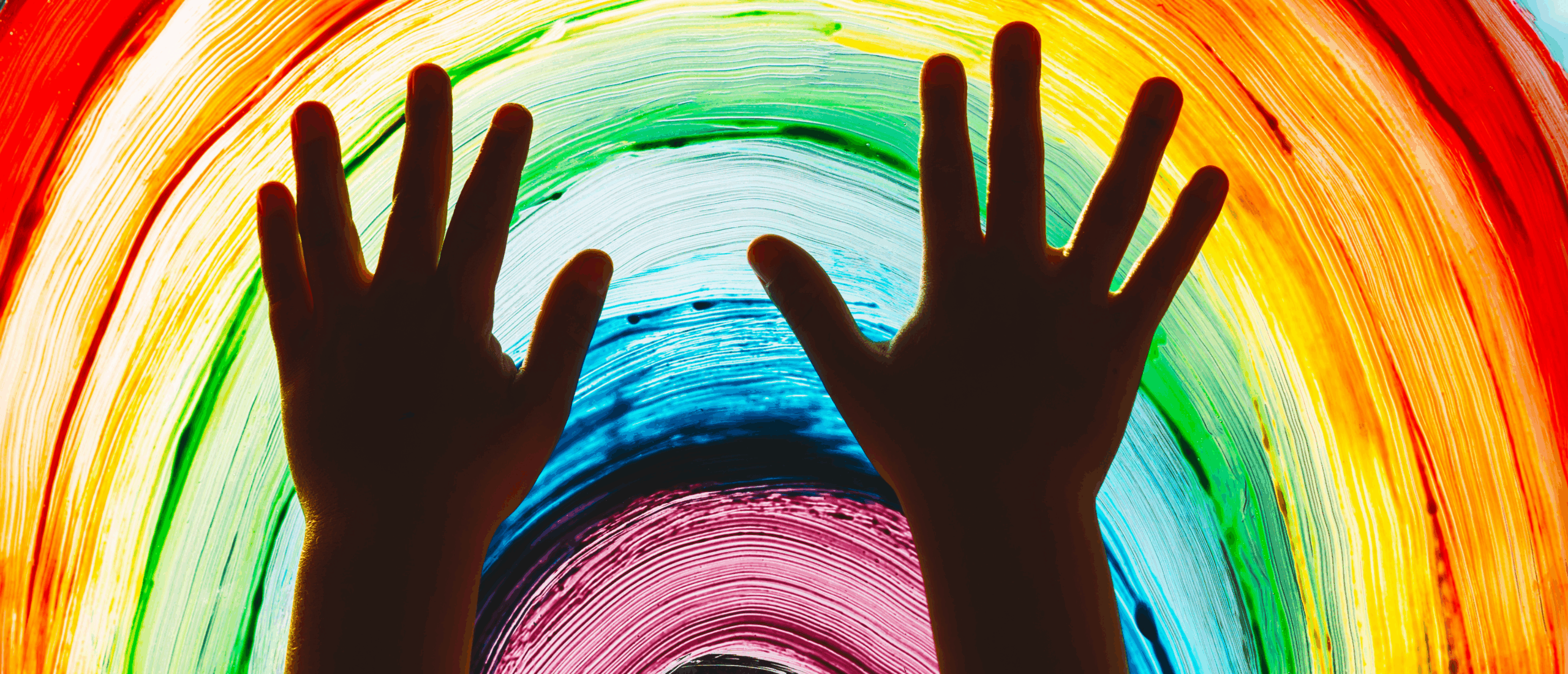 Photo of child's hands against rainbow on glass