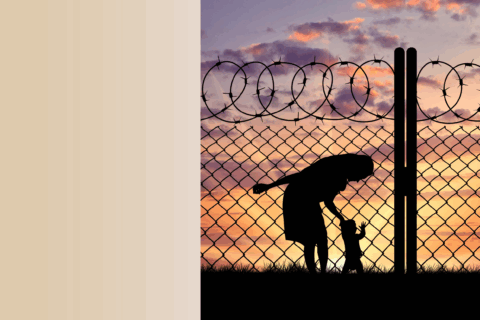 Image of black figure of woman bending over and holding hand of small child against barbed wire fence and sunset.