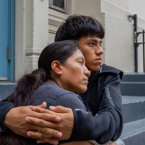 Image of young man embracing his mother while sitting on stone steps.