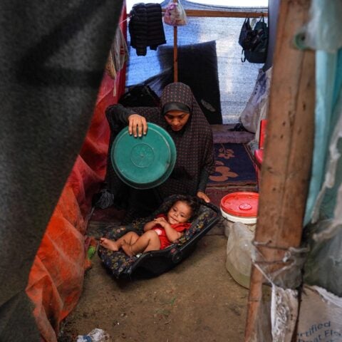 A Palestinian woman uses a plastic plate to fan a baby during a heatwave in Gaza in 2024. Bashar Taleb/AFP/via Getty Images