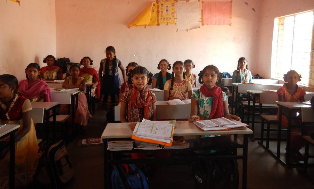 Cute Indian schoolgirls seated at desks
