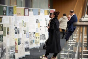 Woman in black coat and sneakers looking at the Legacies of Eugenics exhibition posters at the Martin Center on April 6, 2023.