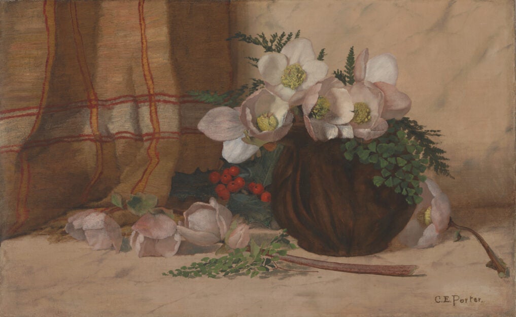 This oil painting depicts a bouquet of off-white roses and greenery in a brown bowl. The round bowl, done in deep brown tones, stands to the right side of the picture. In the bowl are five blooms and several sprays of greenery. Several other blossoms, a sprig of greenery and a long stem lie scattered around the bowl. Peeking from behind the bowl are a pile of darker green leaves and a cluster of bright red berries. Hanging on the left hand background wall is a textile with a yellow, red, and white plaid pattern.