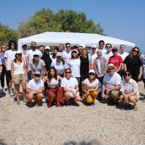 2024 cohort of intensive summer course on migration and refugee studies in Greece posing for group photo by the sea in Lesvos, Greece.